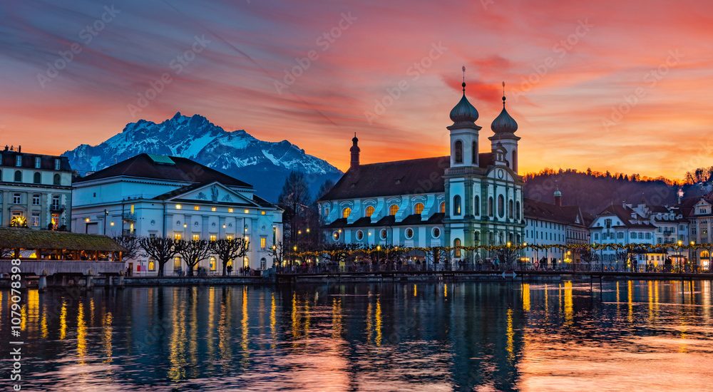 Splended sunset over the  Lucerne Jesuit church with Pilatus mountain at background in the evening and Rathaussteg in Christmas illumination, Switzerland