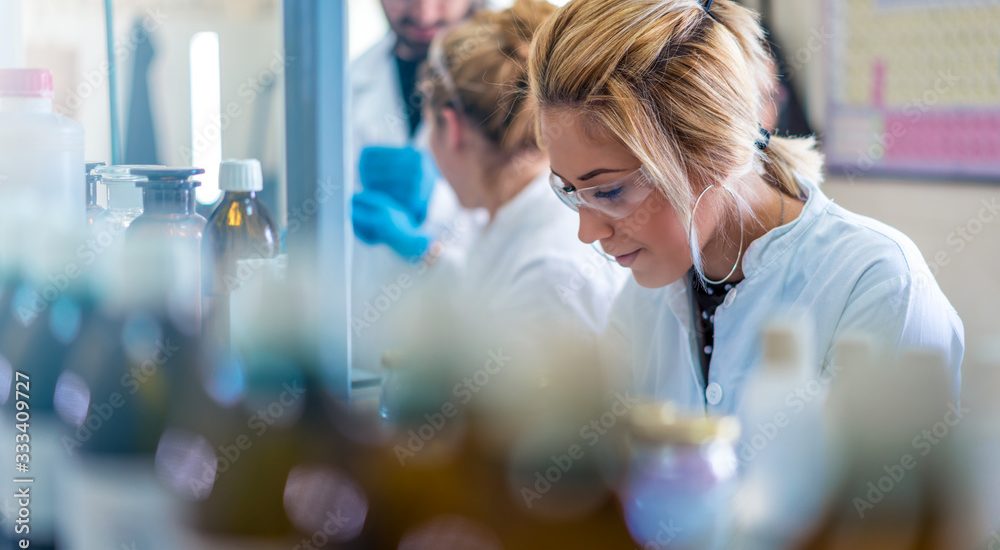 Beautiful young woman scientist in laboratory working. Young female scientist doing some research.