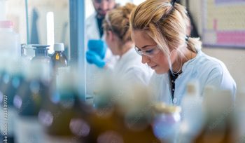 Beautiful young woman scientist in laboratory working. Young female scientist doing some research.