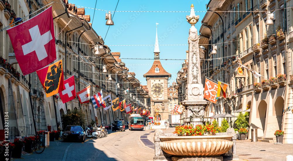 Street view on Kramgasse with fountain and clock tower in the old town of Bern city. It is a popular shopping street and medieval city centre of Bern, Switzerland